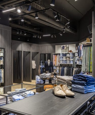 Netjes gevouwen T-shirts en truien op houten planken, met aandacht voor kleur en textuur.