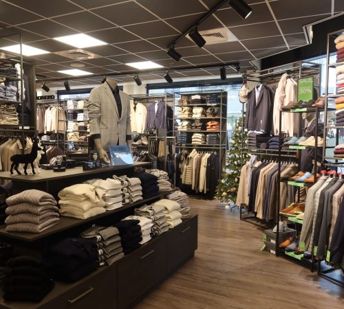 Mannequins tonen een mix van casual en zakelijke outfits in een moderne winkelsetting.