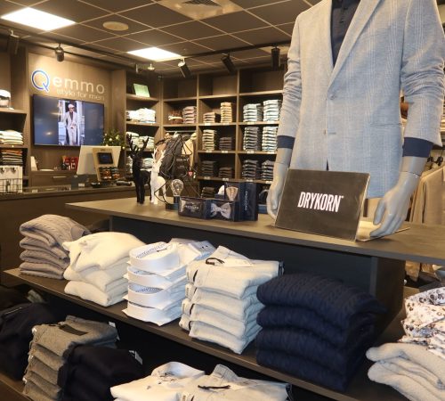 Winkelhoek met kleding van bekende merken en promotiemateriaal, stijlvol gepresenteerd.